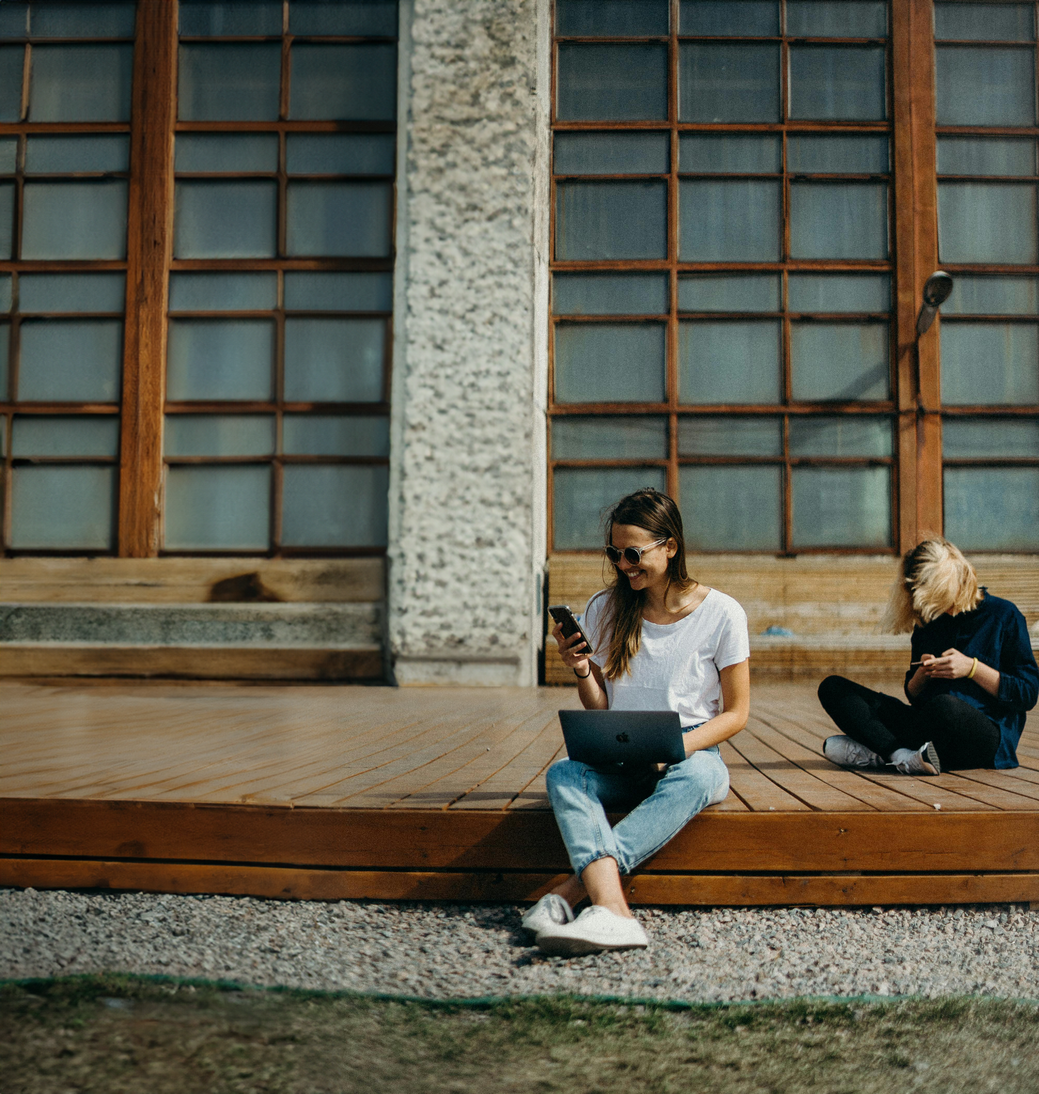 Frauen sitzen mit Smartphone und Laptop auf dem Boden